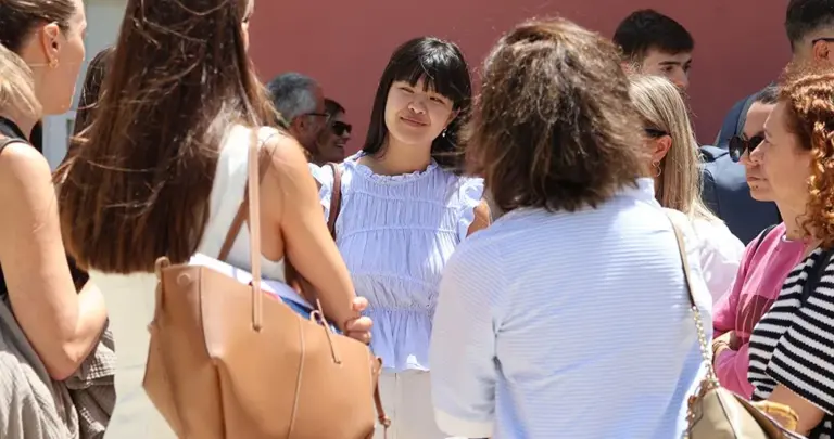 Grupo de personas conversa al aire libre en el Campus de IFFE, una escucha sonriendo