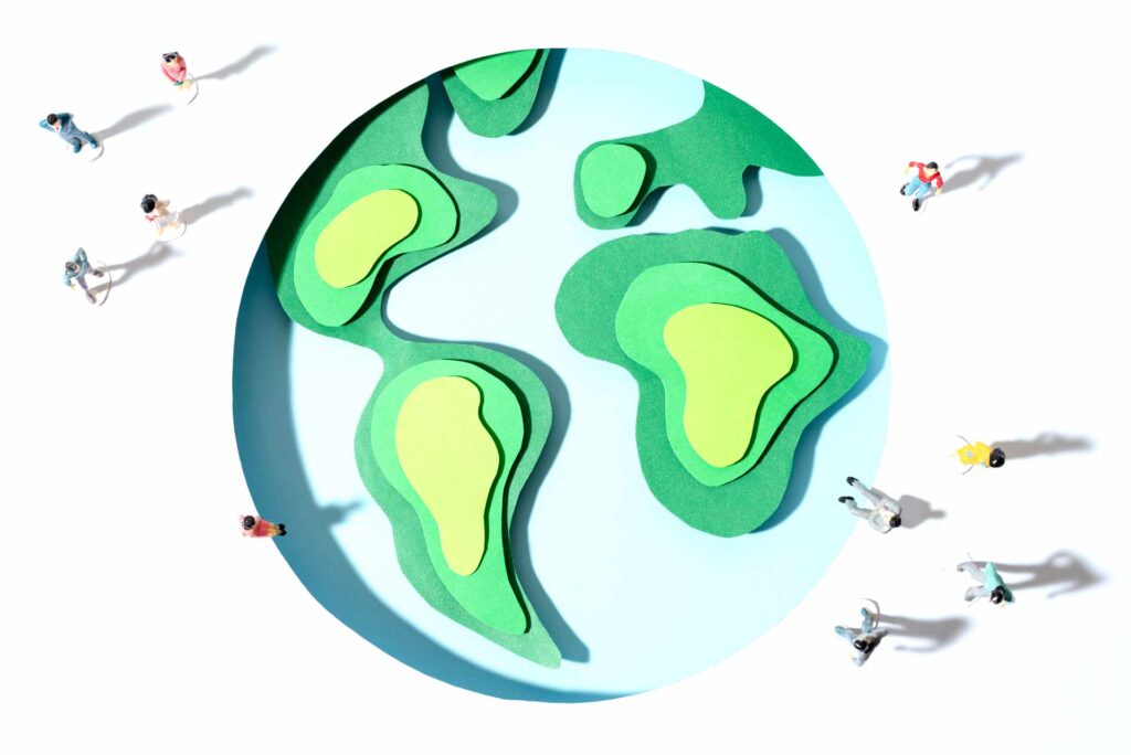 Ilustración del planeta Tierra en papel recortado con pequeñas personas que caminan a su alrededor