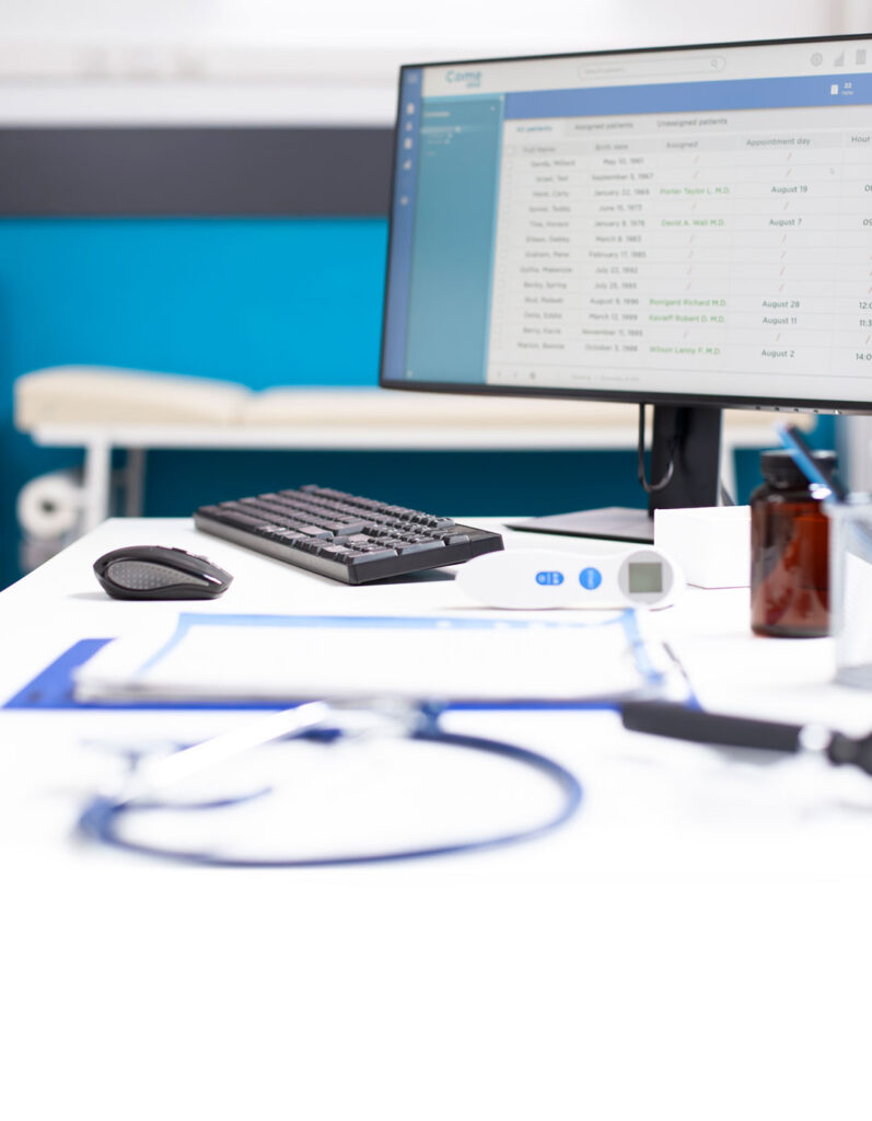 Espacio de trabajo de una gestora sanitaria en el que se ve su ordenador, papeles e instrumental médico