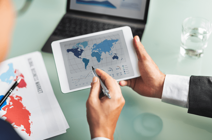 Manos sujetando un ipad con el mapa del mundo