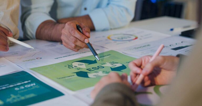 Personas trabajando en una mesa aplicando las finanzas sostenibles a una empresa