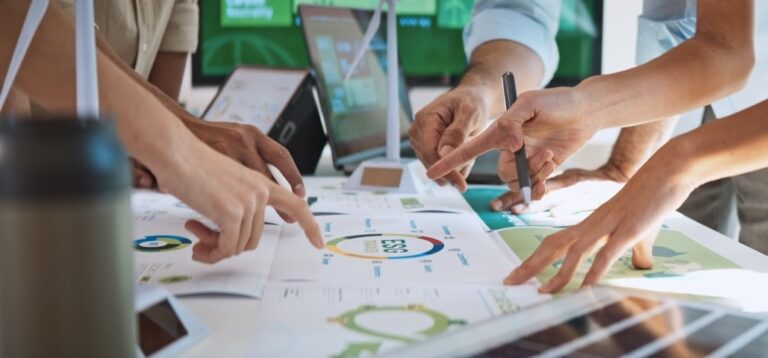 Manos de personas sobre una mesa, trabajando en el crecimiento empresarial
