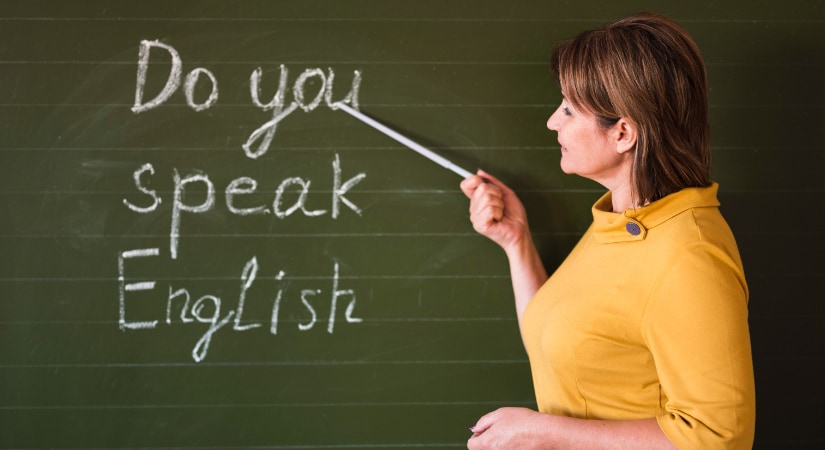 Profesora de inglés en vista lateral explicando en una pizarra verde